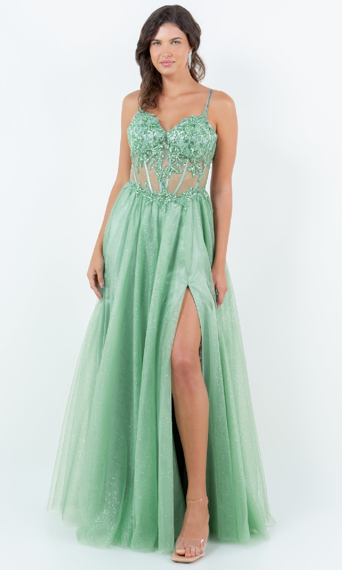 A woman wears the Long Glitter Prom Dress: Cinderella Couture 8238J, a light green sleeveless A-line gown with floral appliqué bodice, sheer panels, sequin lace embroidery, and a high slit, standing against a plain white background.